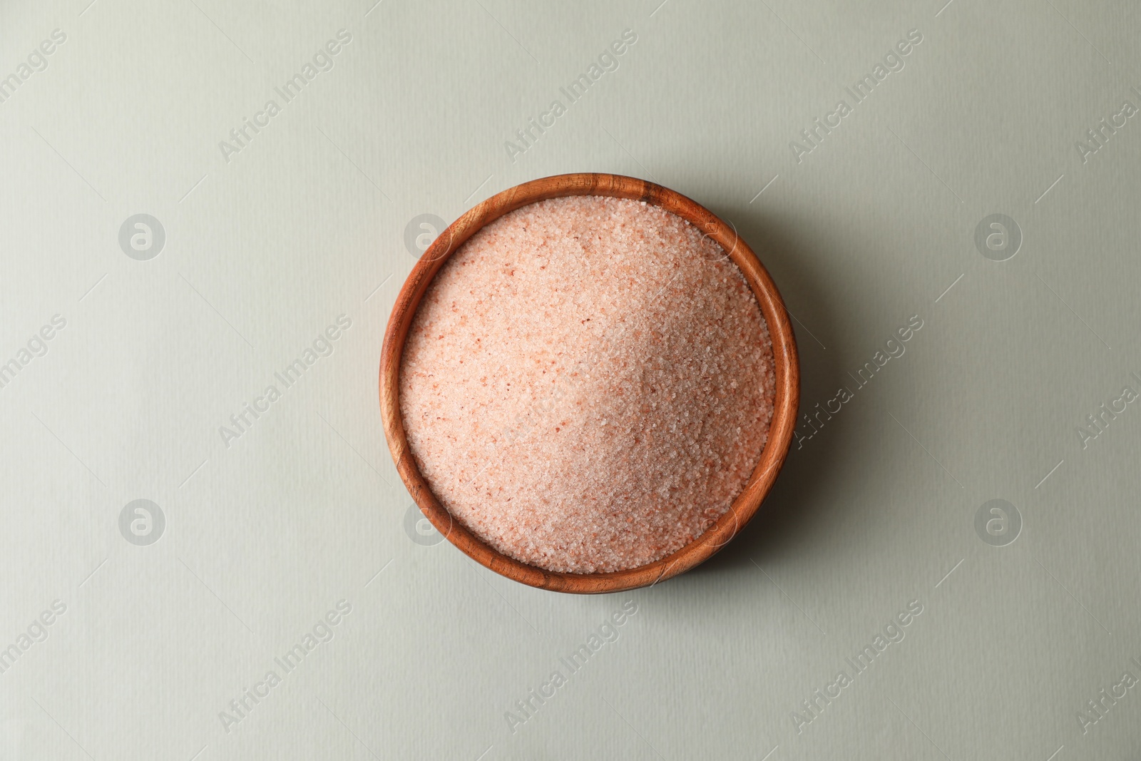 Photo of Himalayan salt in bowl on grey background, top view