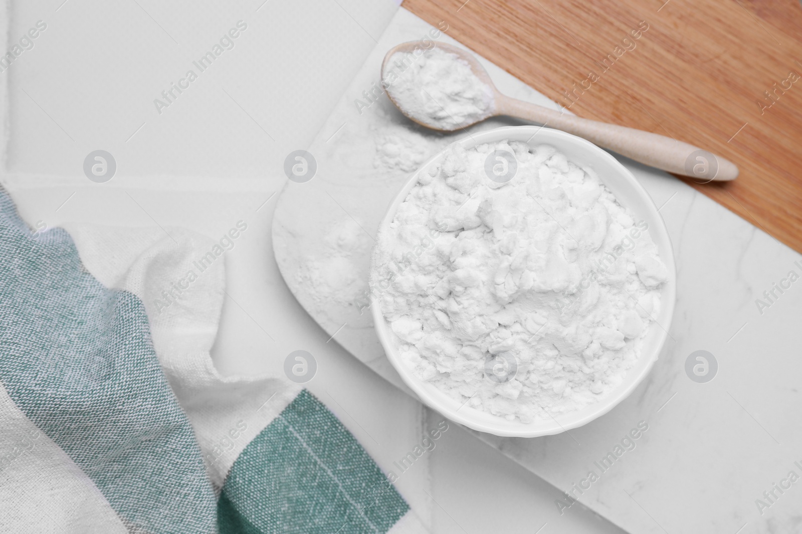 Photo of Bowl and spoon of natural starch on white tiled table, flat lay