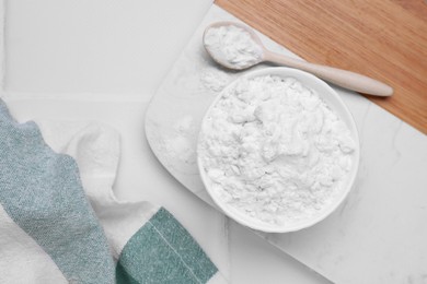 Bowl and spoon of natural starch on white tiled table, flat lay