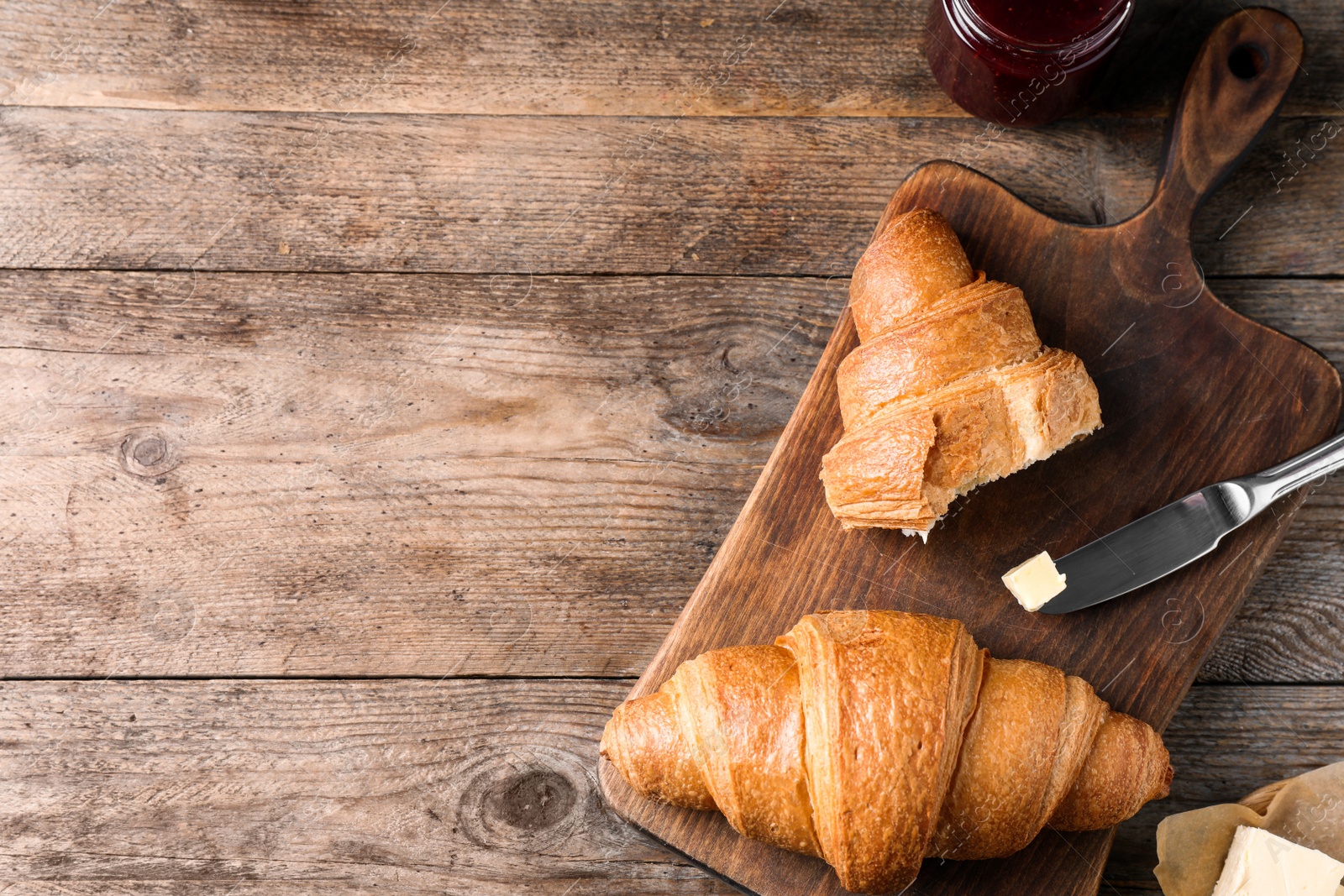 Photo of Tasty fresh croissants on wooden table, flat lay. Space for text