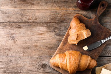 Photo of Tasty fresh croissants on wooden table, flat lay. Space for text