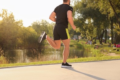 Man running near pond in park, back view