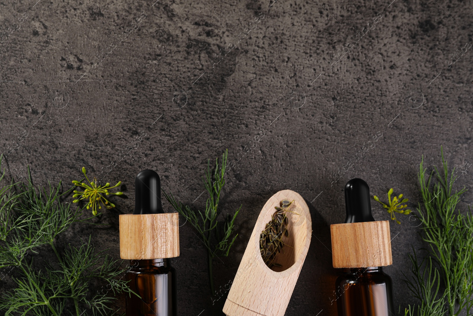 Photo of Bottles of essential oil and scoop with fresh dill on grey table, flat lay. Space for text