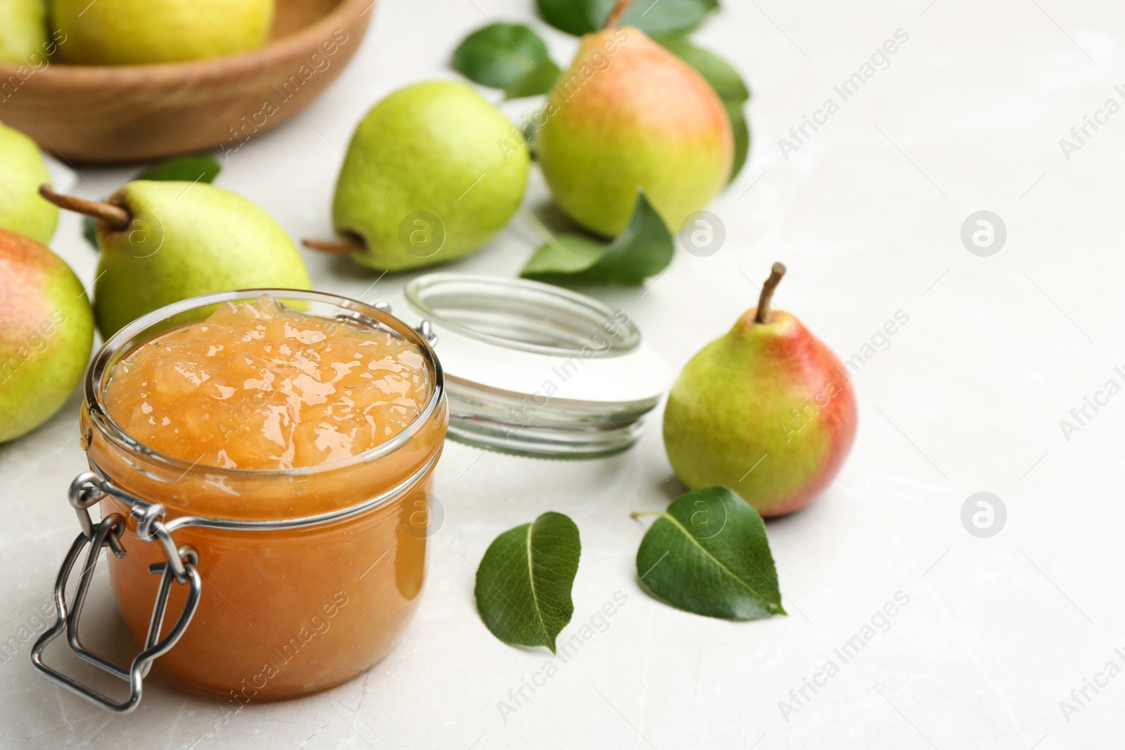Photo of Delicious pear jam and fresh fruits on light grey table. Space for text