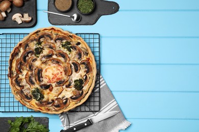Photo of Delicious quiche with mushrooms and ingredients on light blue wooden table, flat lay. Space for text