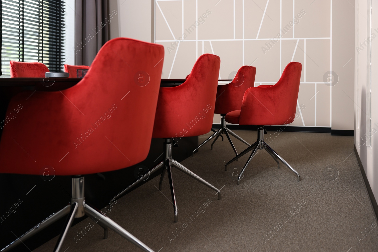 Photo of Stylish red office chairs and large table in empty conference room