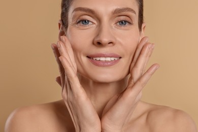 Photo of Woman massaging her face on beige background