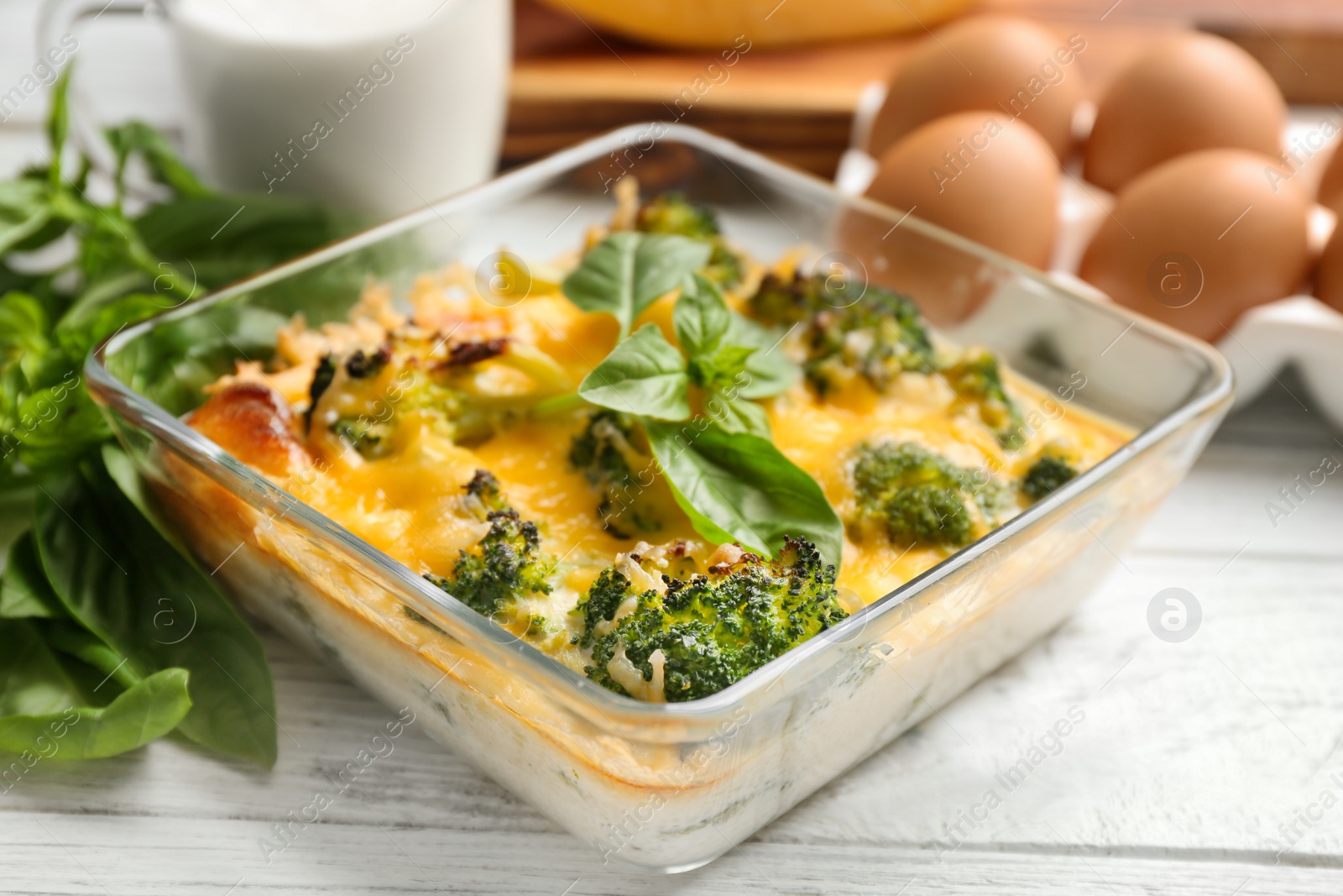 Photo of Tasty broccoli casserole in baking dish on white wooden table