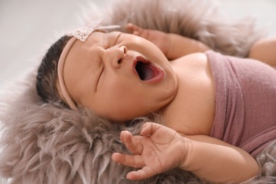 Photo of Cute newborn baby yawning on fuzzy blanket, closeup