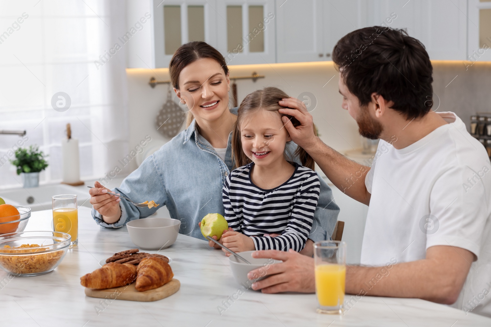 Photo of Happy family having breakfast at table in kitchen