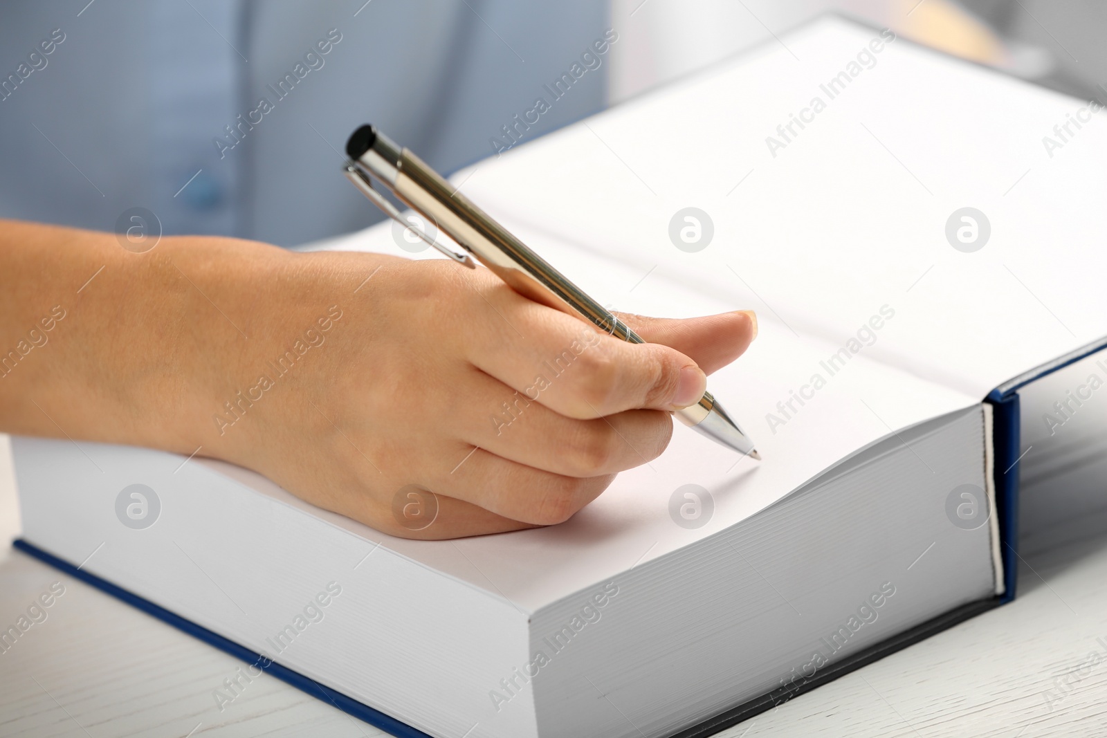Photo of Writer signing autograph in book at table, closeup