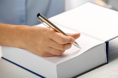 Writer signing autograph in book at table, closeup