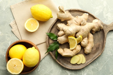 Photo of Fresh lemons and ginger on grey marble table, flat lay