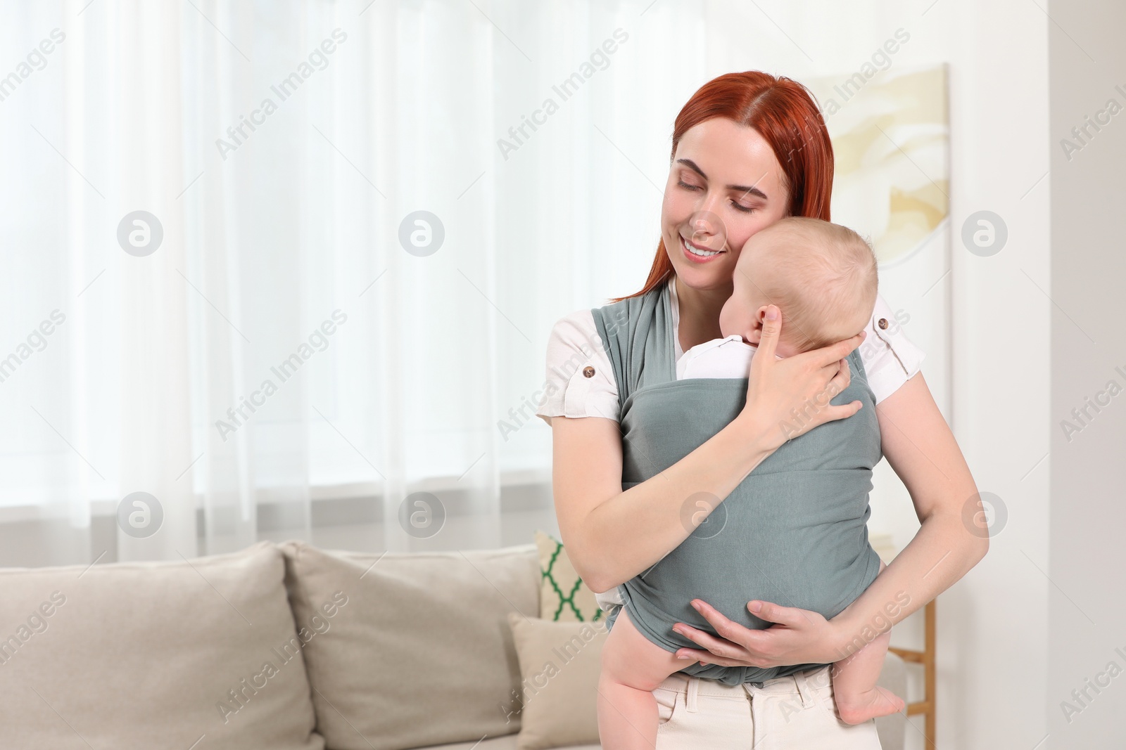 Photo of Mother holding her child in sling (baby carrier) at home