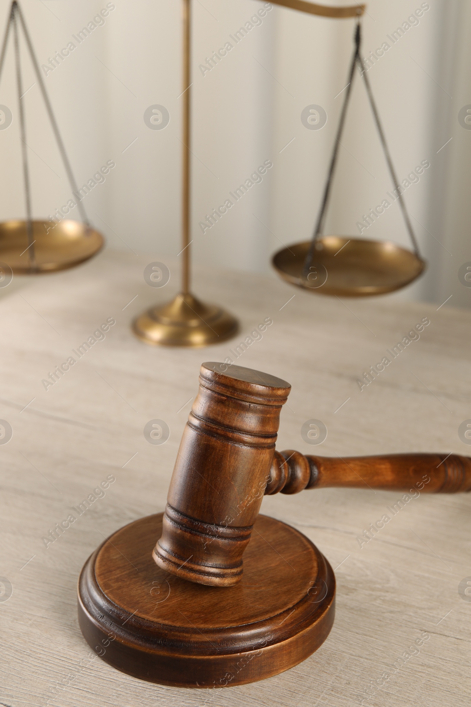 Photo of Law concept. Judge's mallet and scales of justice on light wooden table indoors