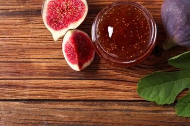 Photo of Jar of tasty sweet jam and fresh figs on wooden table, flat lay. Space for text