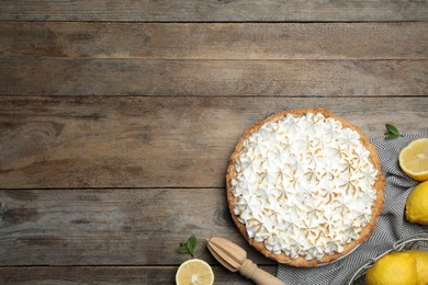 Flat lay composition with delicious lemon meringue pie on wooden table, space for text