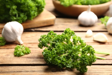 Fresh curly parsley and garlic on wooden table