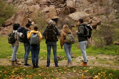 Photo of Group of hikers with backpacks in mountains, back view