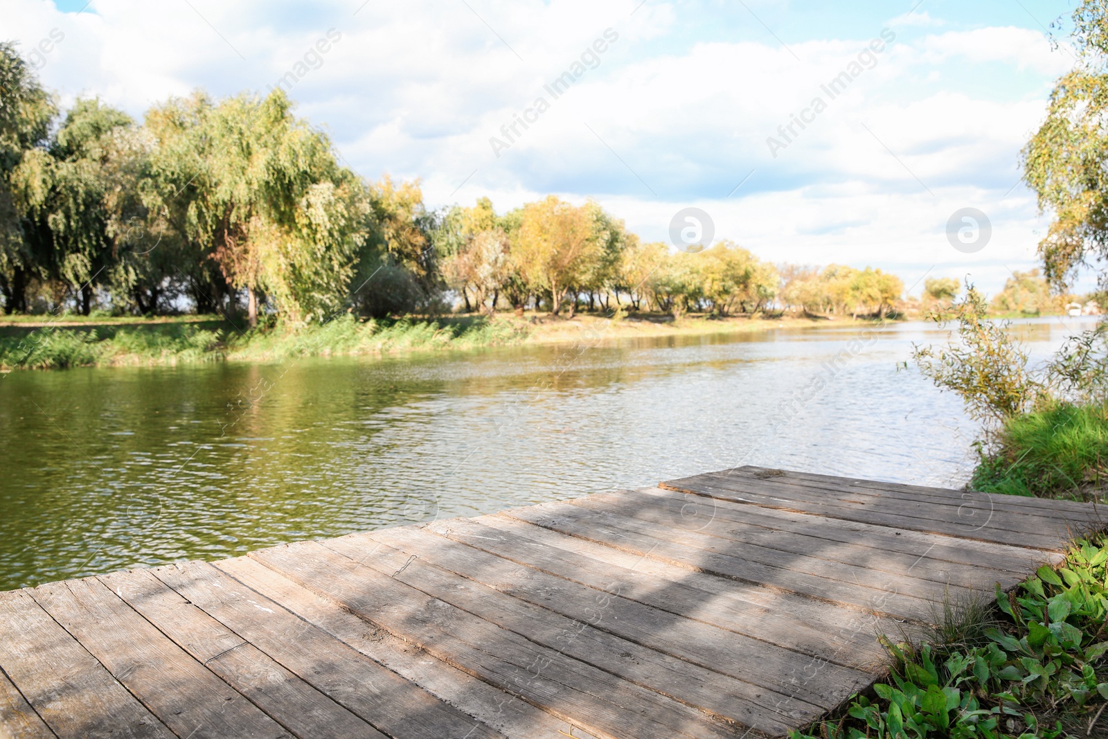 Photo of Wooden pier near river on sunny day. Perfect place for fishing