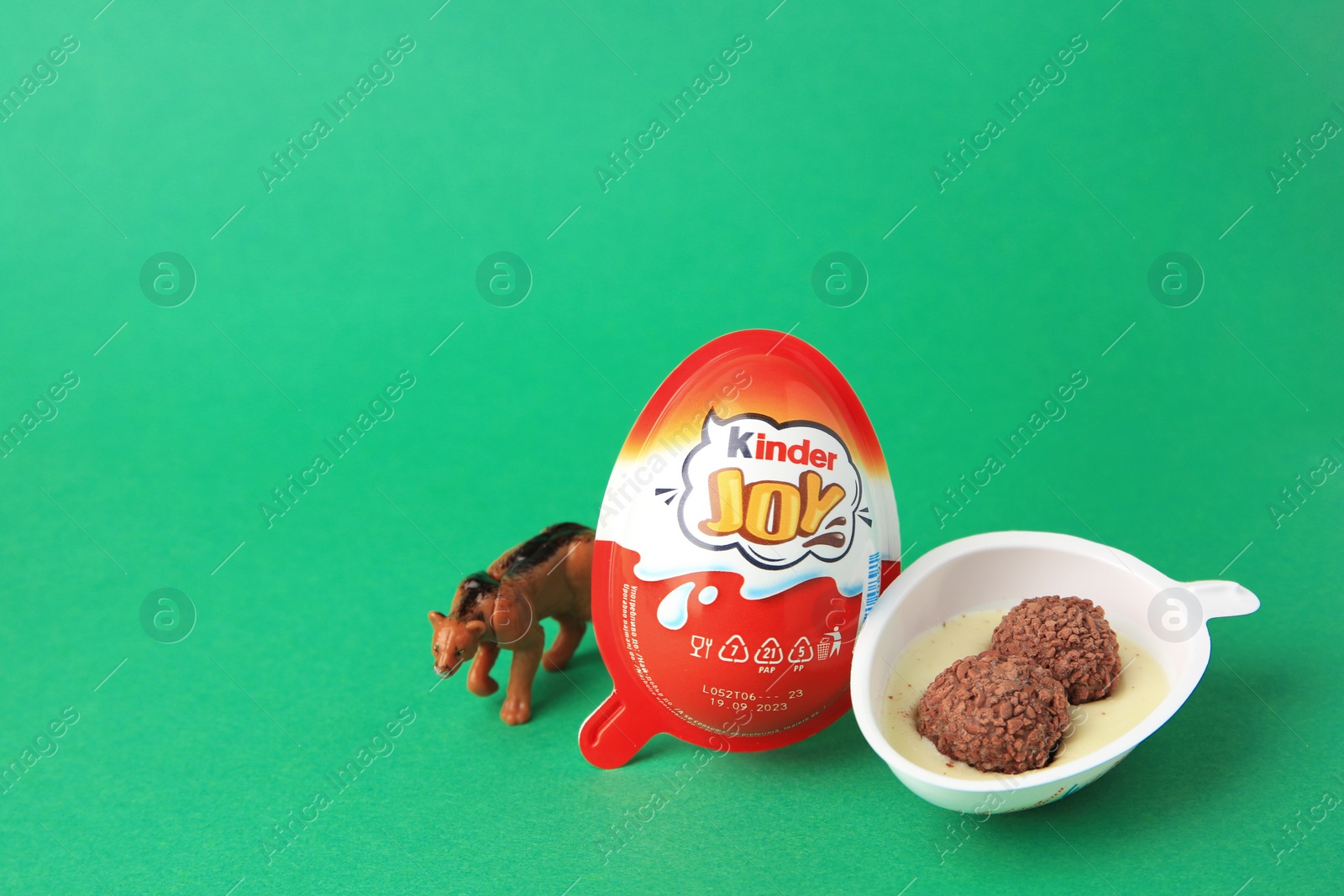 Photo of Slynchev Bryag, Bulgaria - May 25, 2023: Kinder Joy Egg with sweet candies and toy on green background, space for text