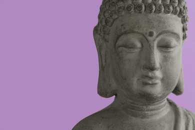 Photo of Beautiful stone Buddha sculpture on violet background, closeup. Space for text