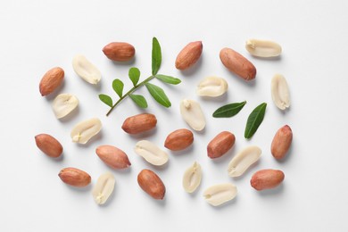 Photo of Fresh peanuts and green leaves on white background, flat lay