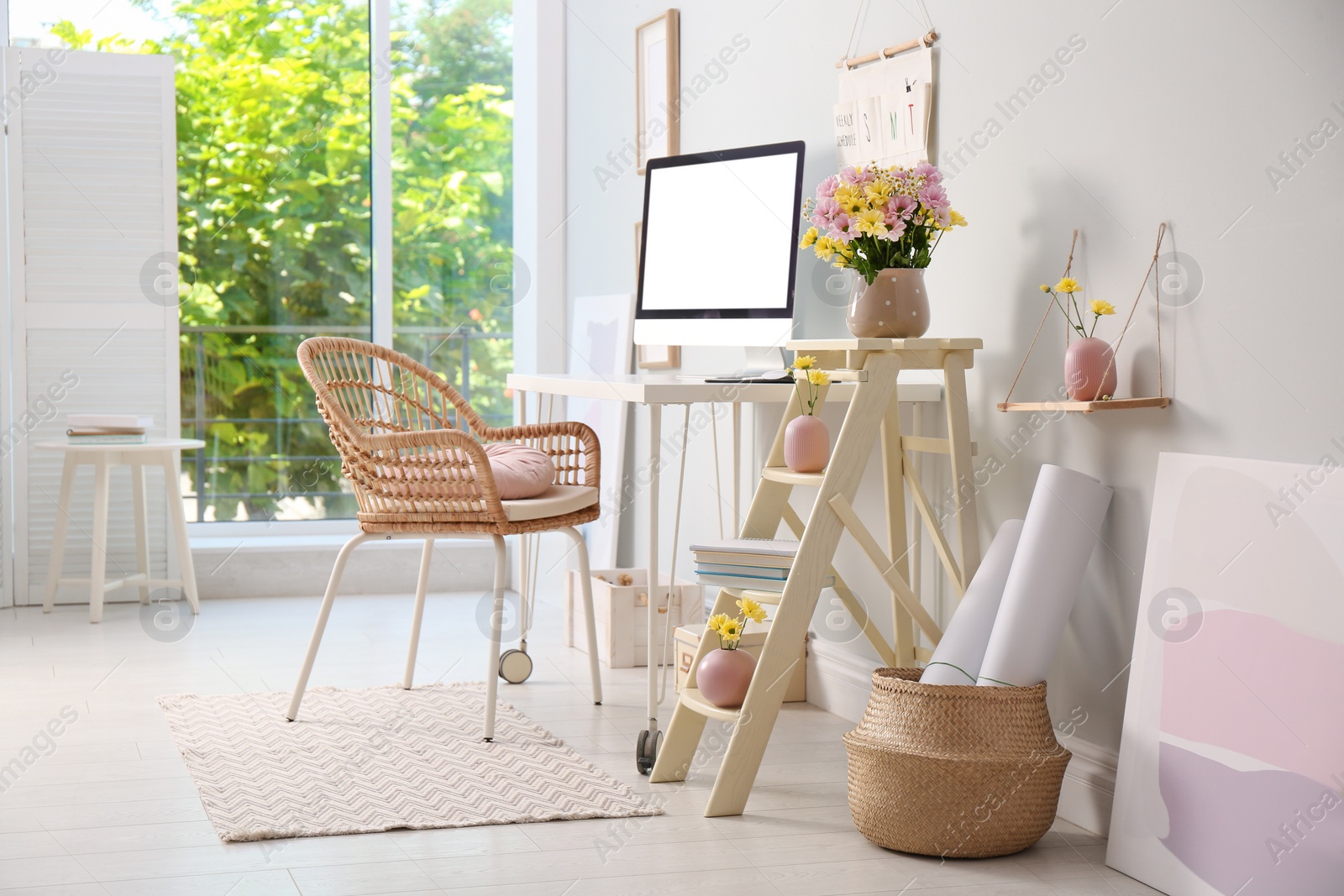 Photo of Comfortable workplace with modern computer and flowers in room. Interior design