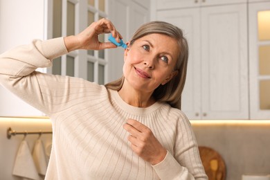 Photo of Woman applying medical ear drops at home