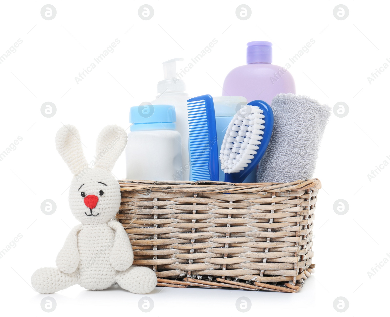 Photo of Wicker basket with baby cosmetic products and knitted rabbit isolated on white