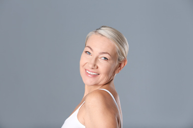 Portrait of beautiful mature woman on grey background