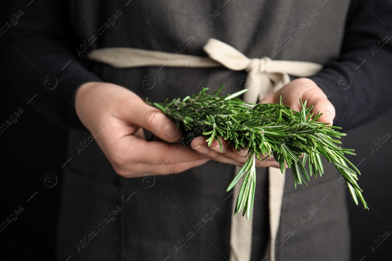 Photo of Young woman holding bunch of fresh rosemary, closeup