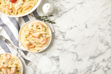 Delicious pasta with shrimps served on white marble table, flat lay. Space for text