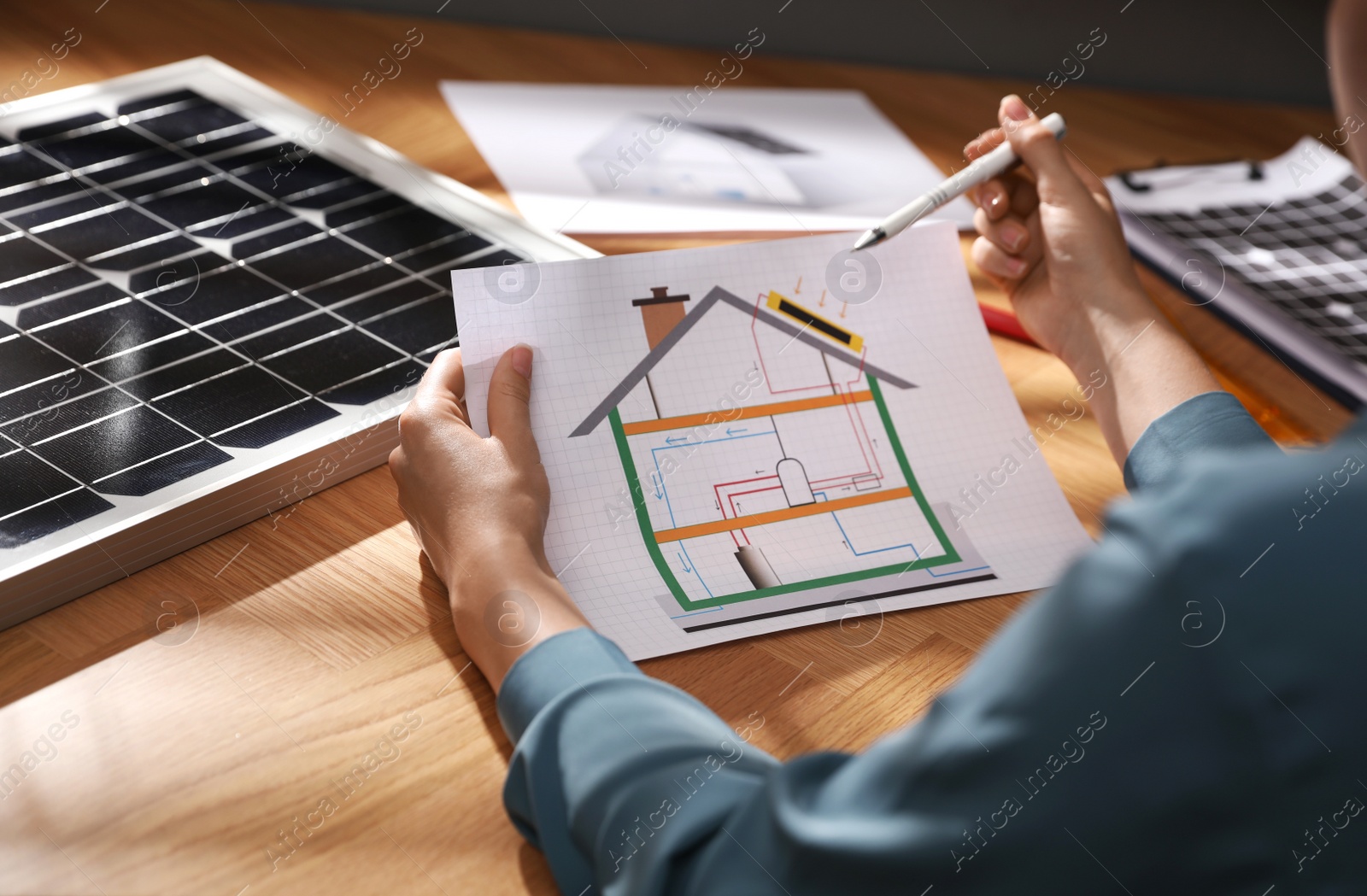 Photo of Woman working on house project with solar panels at table in office, closeup