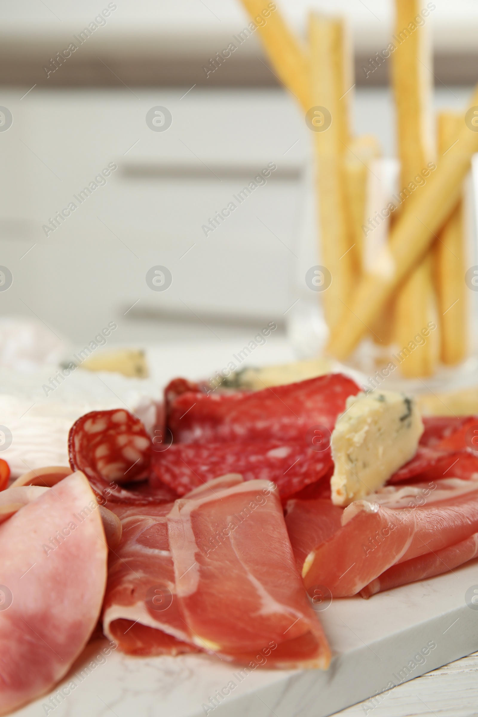 Photo of Tasty ham with other delicacies served on white wooden table, closeup