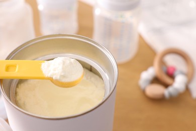 Photo of Can of powdered infant formula with scoop on table, closeup. Baby milk