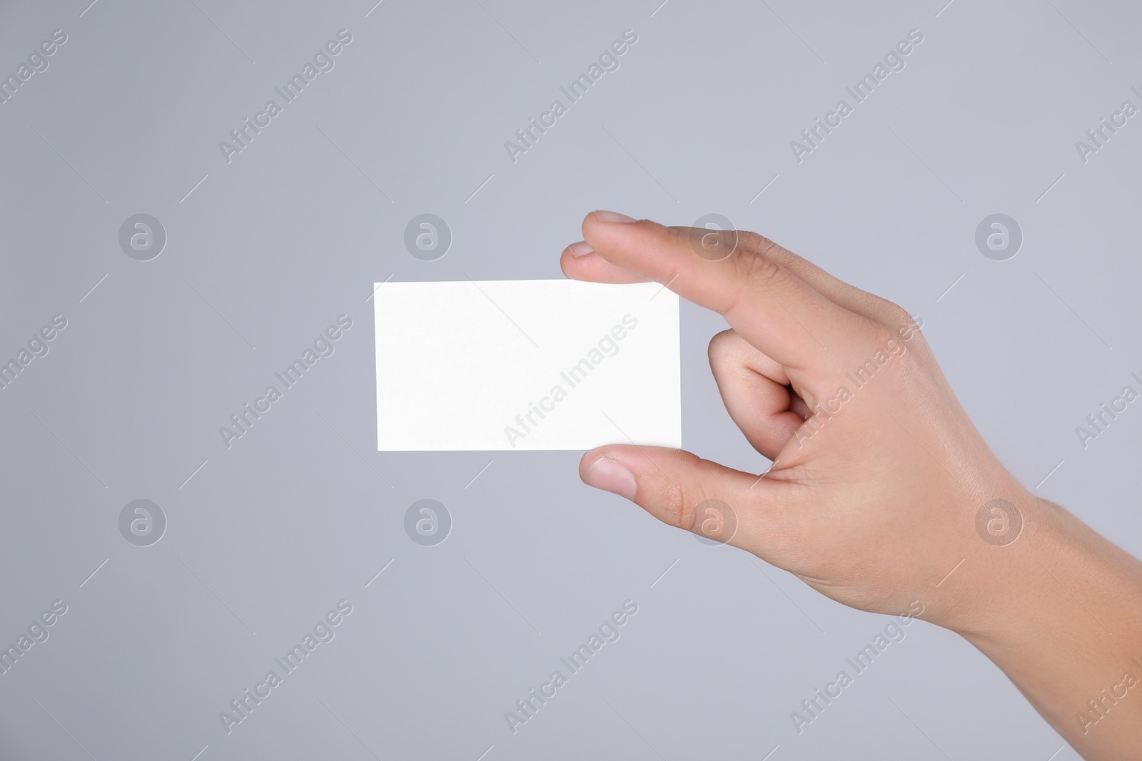 Photo of Man holding blank business card on grey background, closeup. Mock up for design