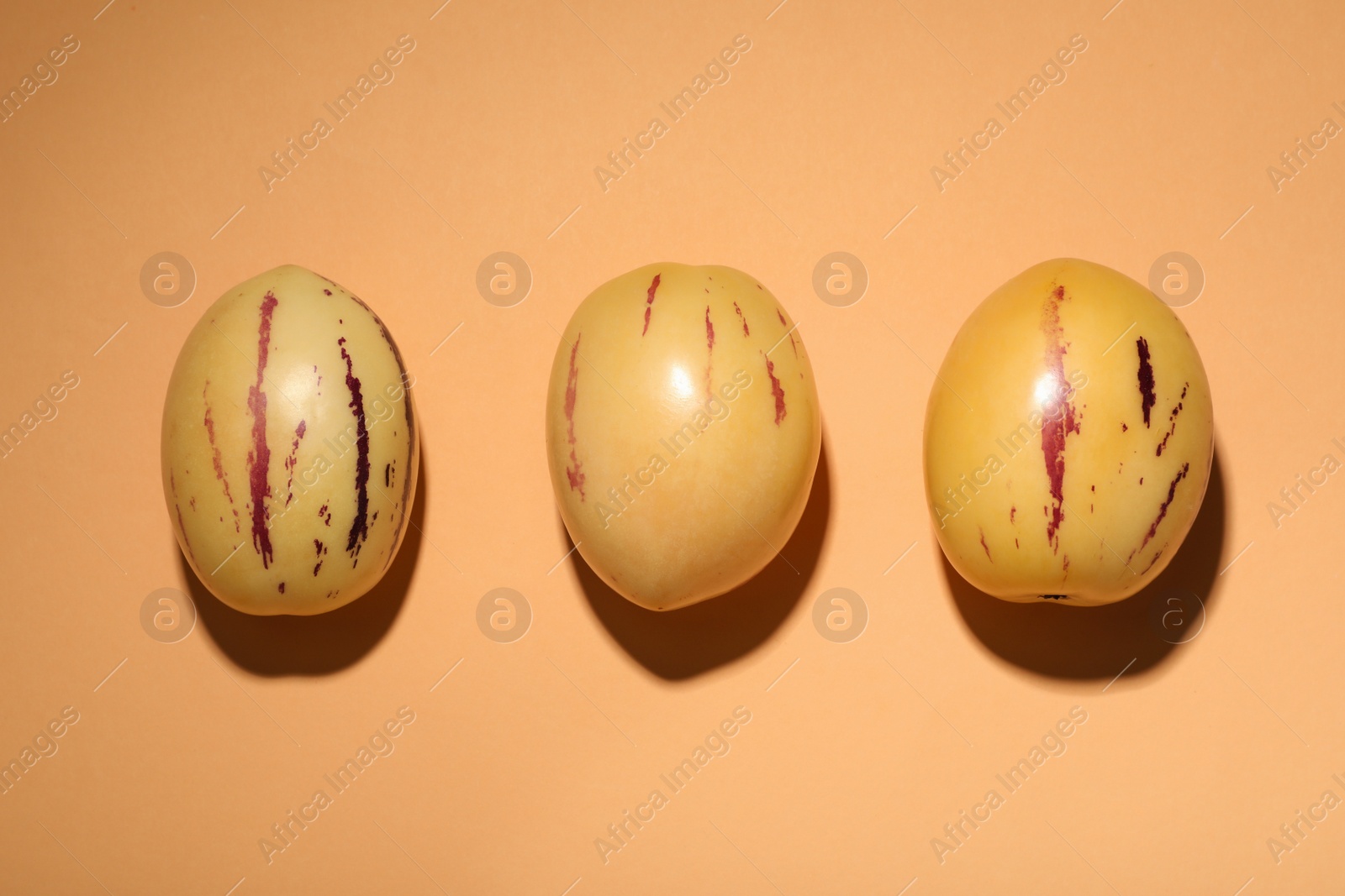 Photo of Fresh ripe pepino melons on orange background, flat lay