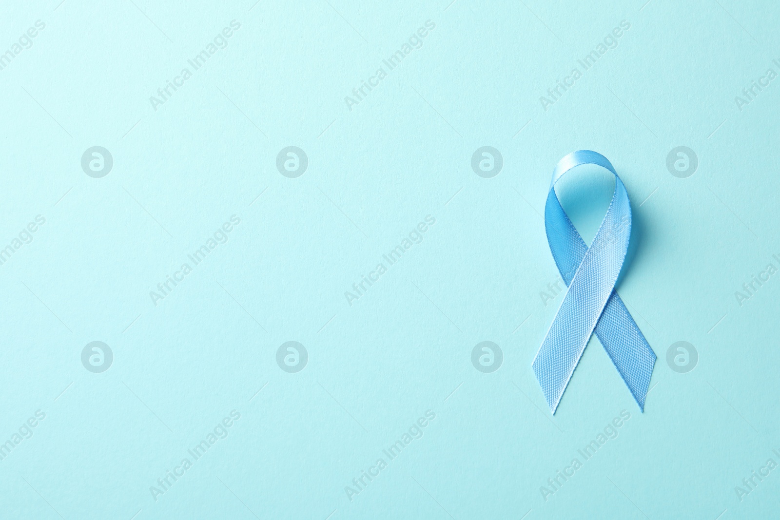 Photo of Blue ribbon on color background, top view. Cancer awareness