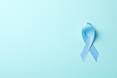 Photo of Blue ribbon on color background, top view. Cancer awareness