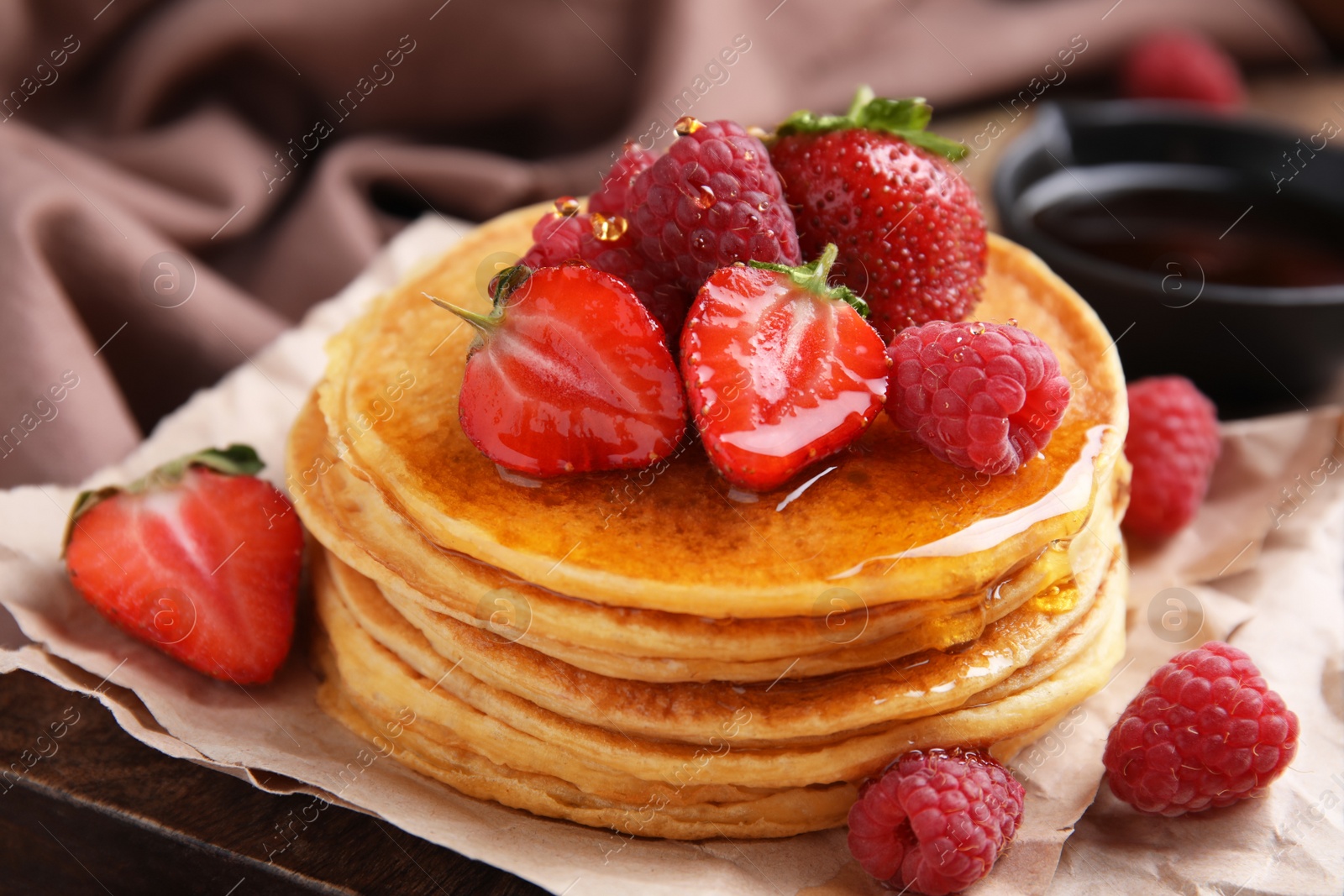 Photo of Tasty pancakes with fresh berries and honey on wooden board, closeup