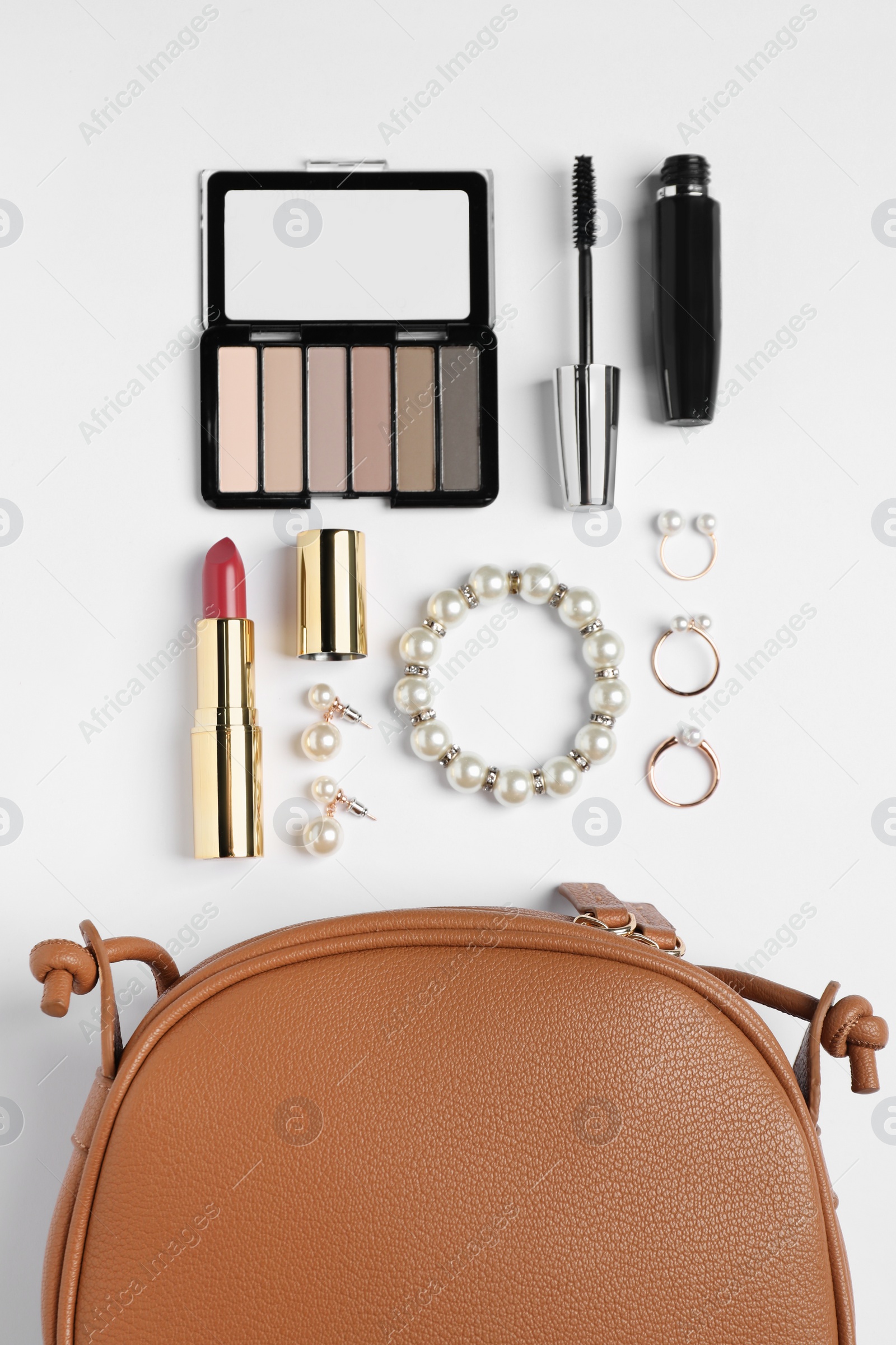 Photo of Stylish leather handbag and makeup items on white background, flat lay