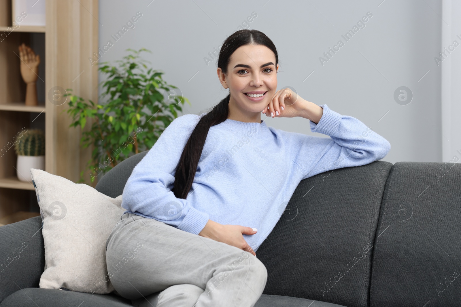 Photo of Happy pregnant woman on sofa at home