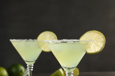 Photo of Delicious Margarita cocktail with salt and lime against blurred background, closeup