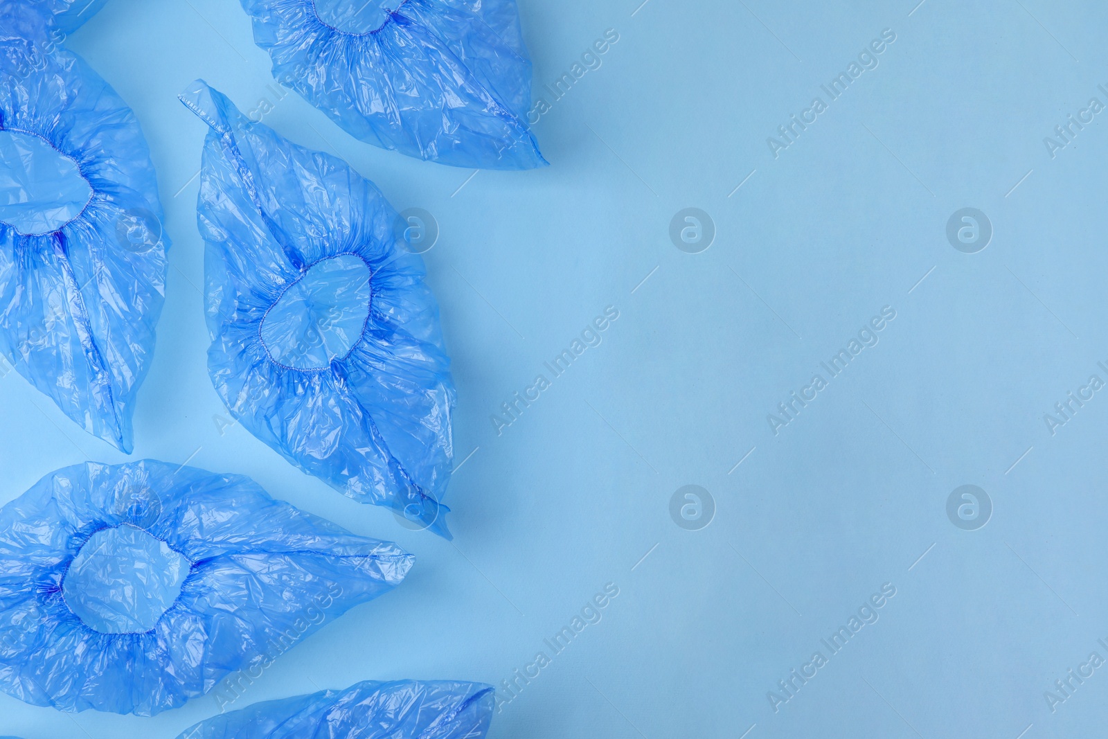 Photo of Medical shoe covers on light blue background, flat lay. Space for text