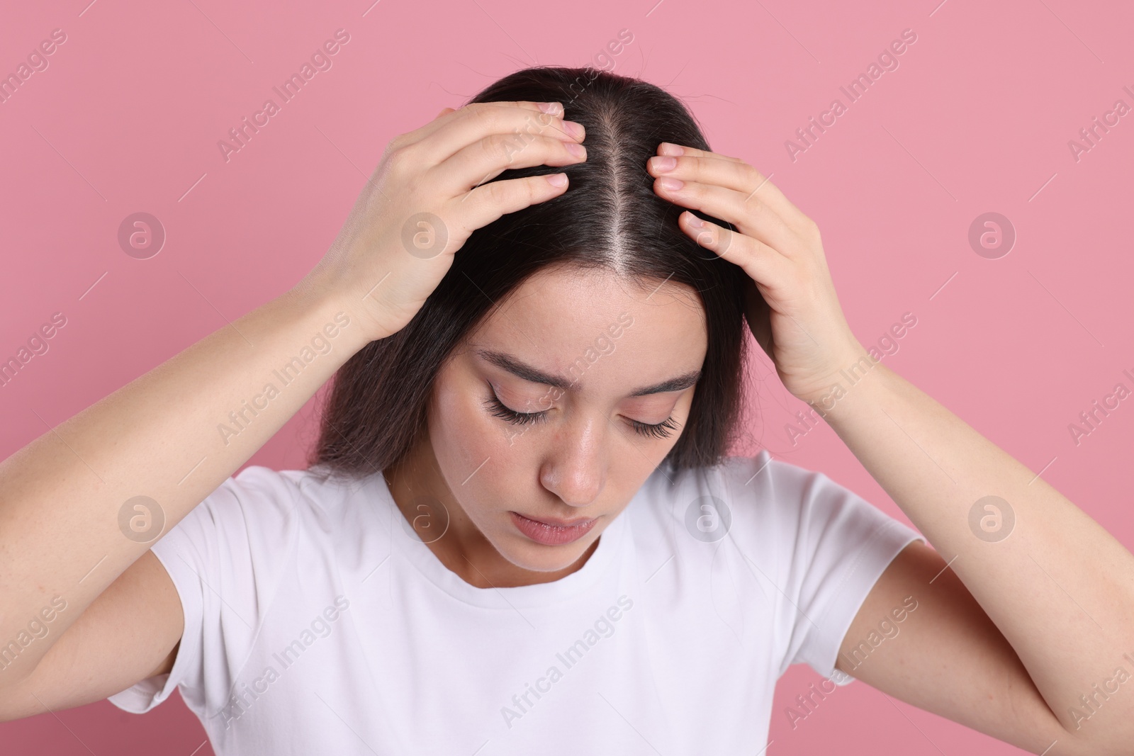 Photo of Woman examining her hair and scalp on pink background