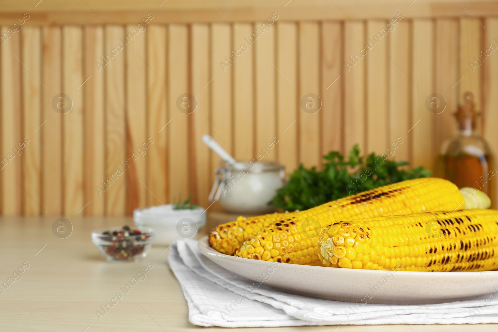 Photo of Plate with tasty grilled corn on wooden table. Space for text