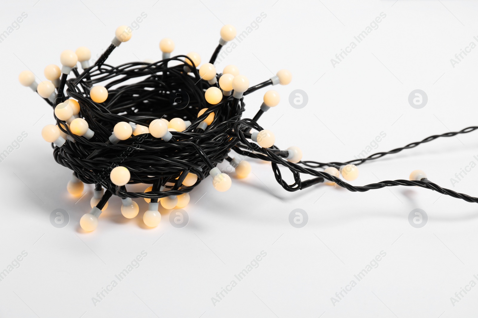 Photo of Beautiful Christmas lights on white background, closeup