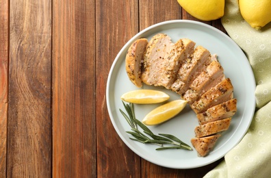 Photo of Tasty lemon chicken on wooden table, flat lay. Space for text