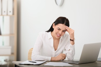 Photo of Woman suffering from migraine at workplace in office, space for text